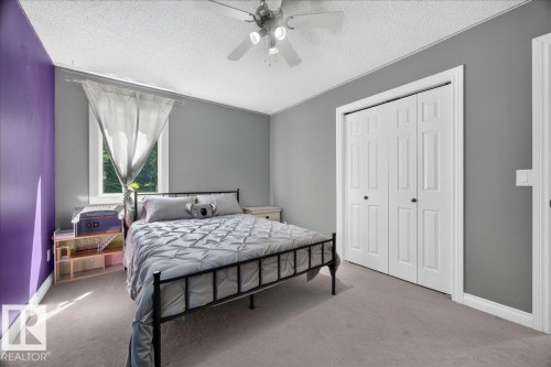 Carpeted room featuring a ceiling fan with integrated lighting, a window with natural light, and a set of bi-fold closet doors - #47 21061 Wye Rd, Rural Strathcona County, AB - Indoor Photo Showing Bedroom