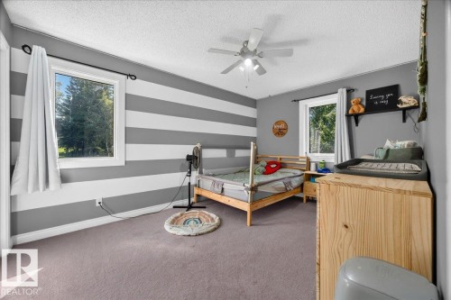 Spacious room featuring two windows with white trim, gray and white striped accent walls, and neutral carpeting - #47 21061 Wye Rd, Rural Strathcona County, AB - Indoor Photo Showing Bedroom