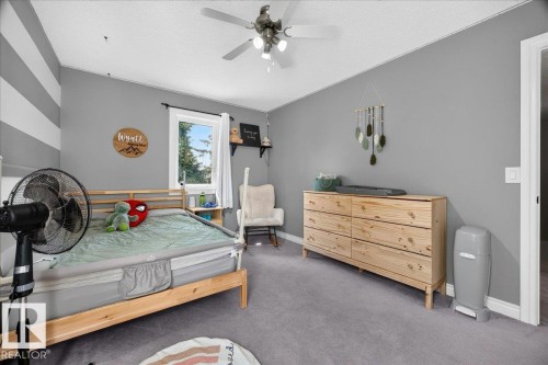 Carpeted room featuring a ceiling fan with integrated lighting, a window with a white frame, and a wide wooden dresser with six drawers - #47 21061 Wye Rd, Rural Strathcona County, AB - Indoor Photo Showing Bedroom