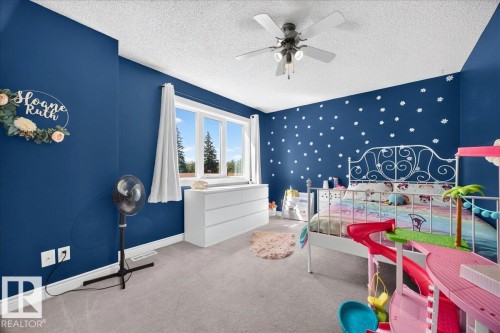 Bright interior space featuring a multi-pane window, ceiling fan with integrated lighting, wall-to-wall carpeting, and baseboard trim - #47 21061 Wye Rd, Rural Strathcona County, AB - 