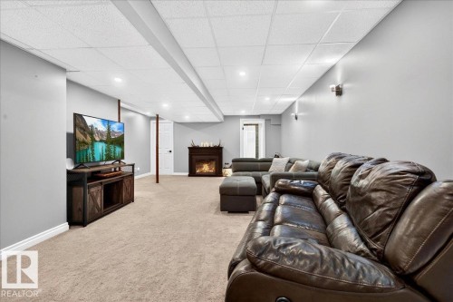 Carpeted room featuring a drop ceiling with recessed lighting and a built-in fireplace - #47 21061 Wye Rd, Rural Strathcona County, AB - Indoor