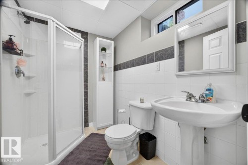 Bathroom featuring a glass-enclosed shower, pedestal sink, and built-in storage cabinet with glass shelving - #47 21061 Wye Rd, Rural Strathcona County, AB - Indoor Photo Showing Bathroom