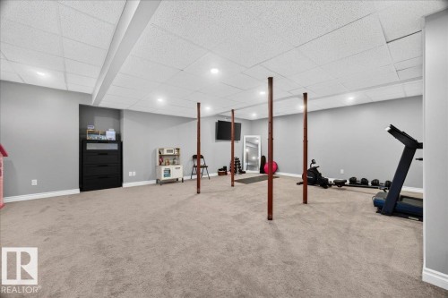 Spacious carpeted room featuring a drop ceiling with recessed lighting and light gray wall paint - #47 21061 Wye Rd, Rural Strathcona County, AB - Indoor Photo Showing Basement