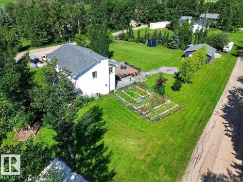 Expansive property featuring a white-sided residence with a dark shingle roof, a detached structure, and extensive green space - #47 21061 Wye Rd, Rural Strathcona County, AB - Outdoor