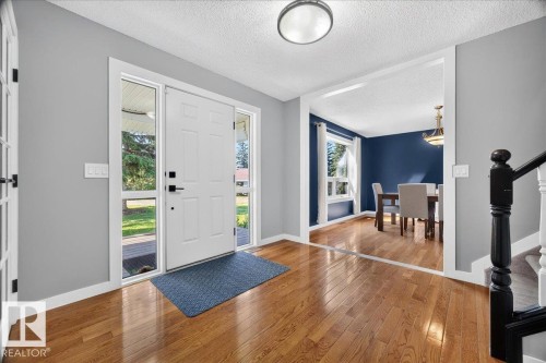 Entryway featuring wood-finish flooring, a paneled front door with sidelights, and overhead lighting - #47 21061 Wye Rd, Rural Strathcona County, AB - Indoor Photo Showing Other Room