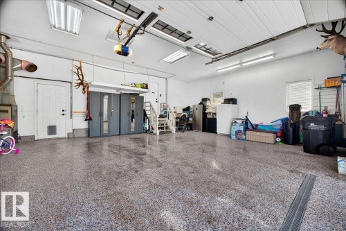 Spacious garage featuring a durable epoxy floor, overhead fluorescent lighting, and a white paneled ceiling - #47 21061 Wye Rd, Rural Strathcona County, AB - Indoor Photo Showing Garage