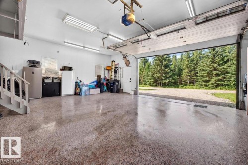 Spacious garage with an open overhead door, textured concrete flooring, and bright overhead lighting - #47 21061 Wye Rd, Rural Strathcona County, AB - Indoor Photo Showing Garage