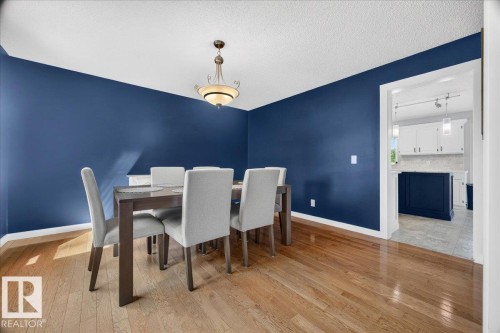 Open dining area featuring wood-finish flooring, a decorative chandelier, and a framed doorway - #47 21061 Wye Rd, Rural Strathcona County, AB - Indoor Photo Showing Dining Room