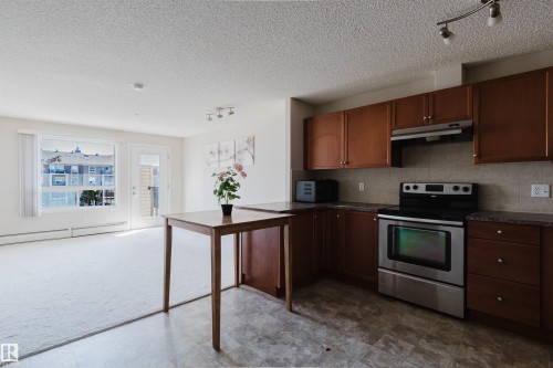 Kitchenette featuring wood-finish cabinetry, stainless steel range and hood, and tiled flooring - #7306 7327 South Terwillegar Dr Nw, Edmonton, AB - Indoor Photo Showing Kitchen