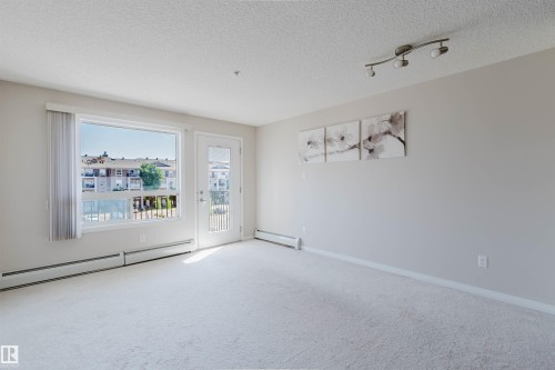 Bright living space featuring light-toned carpet flooring and neutral wall paint - #7306 7327 South Terwillegar Dr Nw, Edmonton, AB - Indoor Photo Showing Other Room