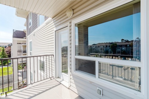 Private balcony featuring a metal railing, concrete flooring, and direct access through a glass-paneled door - #7306 7327 South Terwillegar Dr Nw, Edmonton, AB - Outdoor With Balcony With Exterior