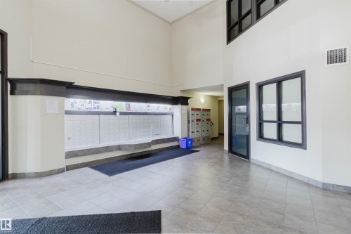 Lobby area featuring light-toned tile flooring, high ceilings, and a wall of individual mailboxes - #7306 7327 South Terwillegar Dr Nw, Edmonton, AB - Indoor