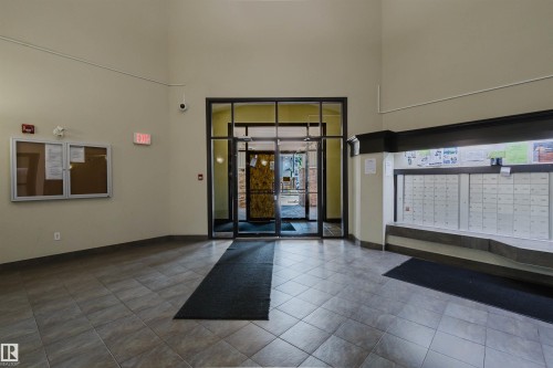 Building entryway featuring tiled flooring, a built-in mail center, glass-paneled double doors, and a bulletin board - #7306 7327 South Terwillegar Dr Nw, Edmonton, AB - Indoor Photo Showing Other Room