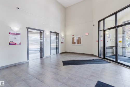 Lobby entrance featuring large format tile flooring, twin elevators with stainless steel doors, and a double-door glass entry system - #7306 7327 South Terwillegar Dr Nw, Edmonton, AB - Indoor Photo Showing Other Room