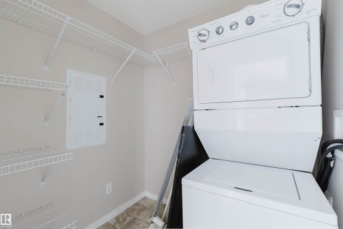 Dedicated laundry area featuring a stacked washer and dryer unit, wire shelving, and neutral wall paint - #7306 7327 South Terwillegar Dr Nw, Edmonton, AB - Indoor Photo Showing Laundry Room