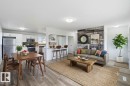 Open-concept living space featuring wood-finish flooring, a kitchen with white cabinetry and stainless steel appliances, and a breakfast bar - 13524 62 Street Nw, Edmonton, AB  - Indoor Photo Showing Other Room 