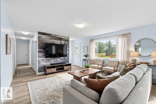 Spacious living area featuring wood-finish flooring, a prominent accent wall with horizontal paneling, and a large window - 13524 62 Street Nw, Edmonton, AB - Indoor Photo Showing Living Room