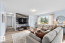 Spacious living area featuring wood-finish flooring, a prominent accent wall with horizontal paneling, and a large window - 13524 62 Street Nw, Edmonton, AB  - Indoor Photo Showing Living Room 