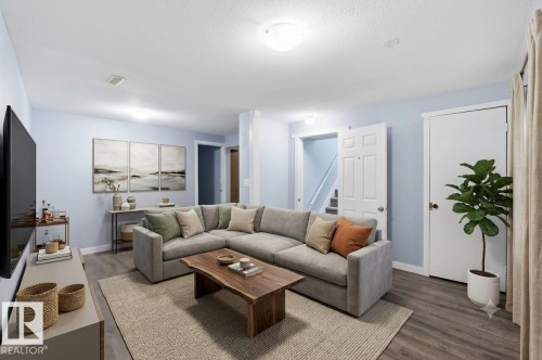 Spacious living area featuring wood-finish flooring, light blue wall paint, recessed lighting, and white trim throughout - 13524 62 Street Nw, Edmonton, AB - Indoor Photo Showing Living Room