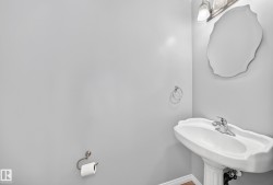 Pedestal sink with chrome faucet, complemented by a decorative wall mirror and a three-light vanity fixture - 