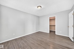 Spacious room featuring wood-finish flooring, light gray wall paint, and white baseboards - 