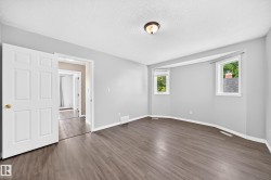 Spacious room featuring wood-finish flooring, light grey walls, and a multi-panel interior door - 