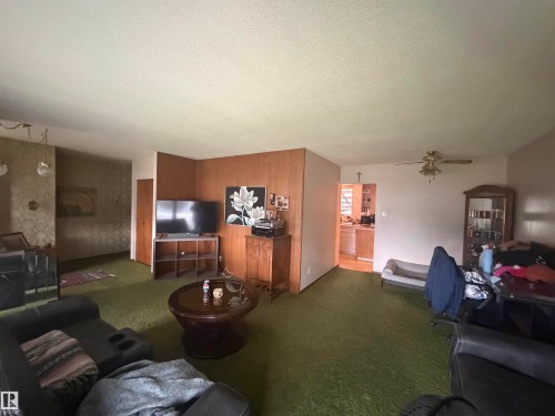 Spacious living area featuring wall paneling and textured wall finishes - 13207 117 Street, Edmonton, AB 