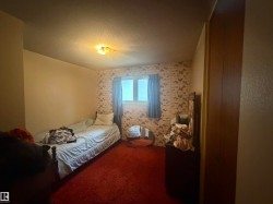 Red carpeted flooring throughout, featuring a window with blue drapes, and a built-in closet with wood-finish doors - 