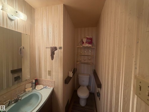 Powder room featuring a vanity with a light blue basin sink, chrome faucet, and a large wall-mounted mirror - 13207 117 Street, Edmonton, AB 