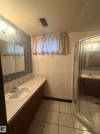 Bathroom featuring a vanity with integrated sink, under-cabinet storage, and an enclosed shower with glass doors - 