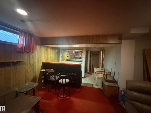 Recreation room featuring wood paneling, red flooring, and a built-in bar - 13207 117 Street, Edmonton, AB 