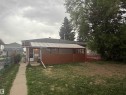 Rear exterior featuring a covered patio, paved walkway, and mature trees - 13207 117 Street, Edmonton, AB 
