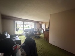 Living area with expansive window wall, textured ceiling, and green carpeting - 