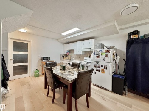 Open-concept kitchen and dining area featuring light wood-finish flooring, white cabinetry, and a full suite of kitchen appliances - #29 13580 38 St Nw, Edmonton, AB - Indoor Photo Showing Dining Room