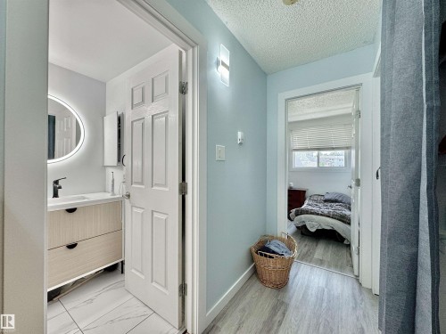 Bathroom featuring a modern vanity with a white countertop, a black faucet, and a round backlit mirror - #29 13580 38 St Nw, Edmonton, AB - Indoor Photo Showing Other Room