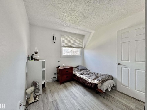 Bedroom featuring wood-finish flooring, white paneled door, and a textured ceiling - #29 13580 38 St Nw, Edmonton, AB - Indoor Photo Showing Bedroom