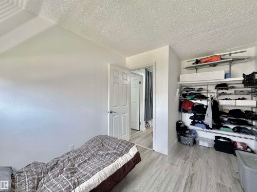 Bedroom featuring light wood-finish flooring, white painted walls, and a built-in closet organization system with wire shelving - #29 13580 38 St Nw, Edmonton, AB - Indoor Photo Showing Bedroom