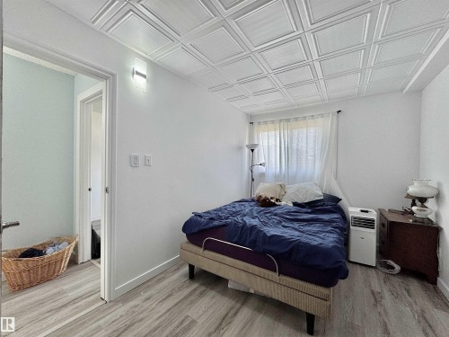 Room featuring a decorative coffered ceiling, light wood-finish flooring, white walls, and a window with sheer curtains - #29 13580 38 St Nw, Edmonton, AB - Indoor Photo Showing Bedroom