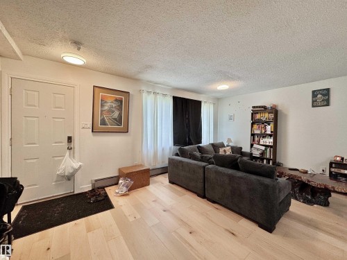 Light wood-finish flooring extends through this room, featuring a paneled entry door with polished hardware - #29 13580 38 St Nw, Edmonton, AB - Indoor Photo Showing Living Room