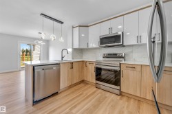 Contemporary kitchen featuring an integrated island, stainless steel appliances, light wood-finish flooring, white upper cabinetry, and a patterned backsplash - 