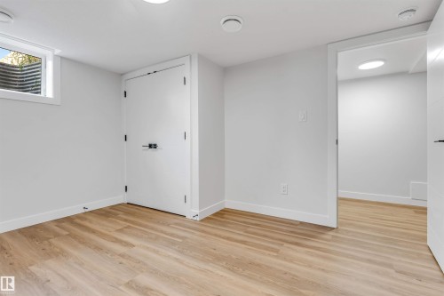 Finished room featuring wood-finish flooring, recessed lighting, and a window well - 1712 27 St Nw, Edmonton, AB - Indoor Photo Showing Other Room