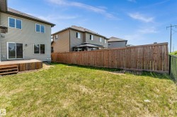 Expansive backyard featuring a wooden deck, sliding glass door, and a full privacy fence - 