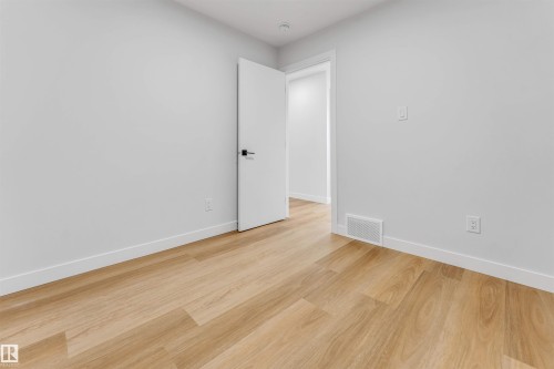Light wood-finish flooring complements crisp white walls and baseboards - 1714 27 St. Nw, Edmonton, AB - Indoor Photo Showing Other Room