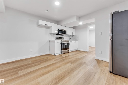 Open-concept room featuring wood-finish flooring, recessed lighting, and a modern kitchen area - 1714 27 St. Nw, Edmonton, AB - Indoor Photo Showing Kitchen
