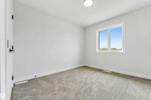 Neutral-toned room featuring a single window with white trim, gray carpet flooring, white baseboards, and a flush-mount ceiling light fixture - 1714 27 St. Nw, Edmonton, AB - Indoor Photo Showing Other Room