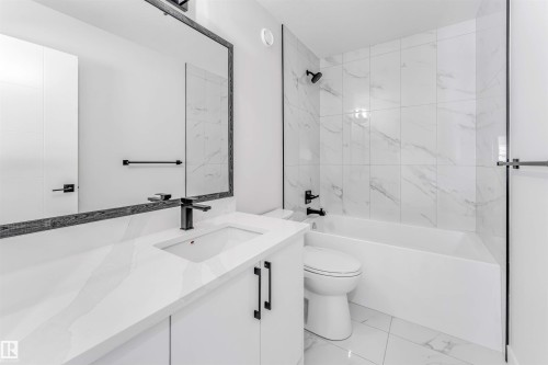Bathroom featuring a white vanity with an integrated sink, black faucet, and a framed mirror - 1714 27 St. Nw, Edmonton, AB - Indoor Photo Showing Bathroom