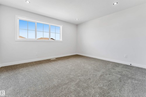 Carpeted room featuring a large multi-pane window, white trim, recessed lighting, and white baseboards - 1714 27 St. Nw, Edmonton, AB - Indoor Photo Showing Other Room
