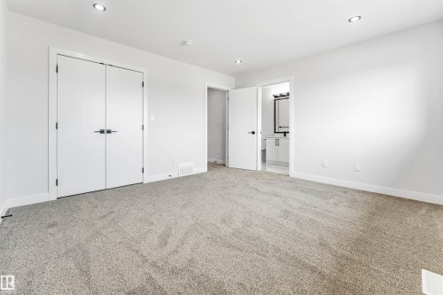Spacious room featuring neutral carpeting, white walls, recessed lighting, and white bi-fold closet doors with dark hardware - 1714 27 St. Nw, Edmonton, AB - Indoor Photo Showing Other Room