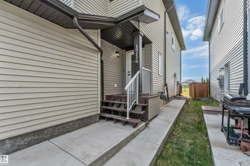 Siding exterior with dark gutters and downspouts, covered entry porch, concrete walkway, and wooden steps with white railing - 1714 27 St. Nw, Edmonton, AB - Outdoor With Exterior