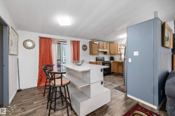 Dining room featuring wood-finish flooring, a white island with bar seating, and a sliding glass door - 